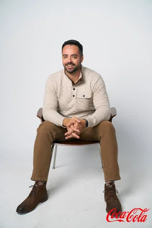 Professional headshot of a man in a cream sweater on a white background