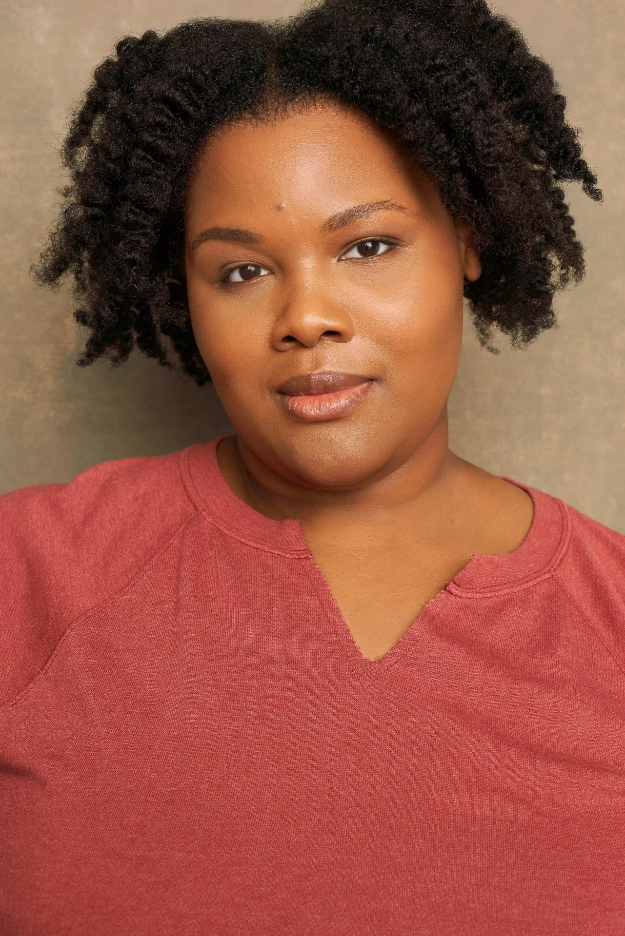 Editorial actor headshot of actress with natural hair in a coral top, photographed by an Atlanta actor headshot photographer