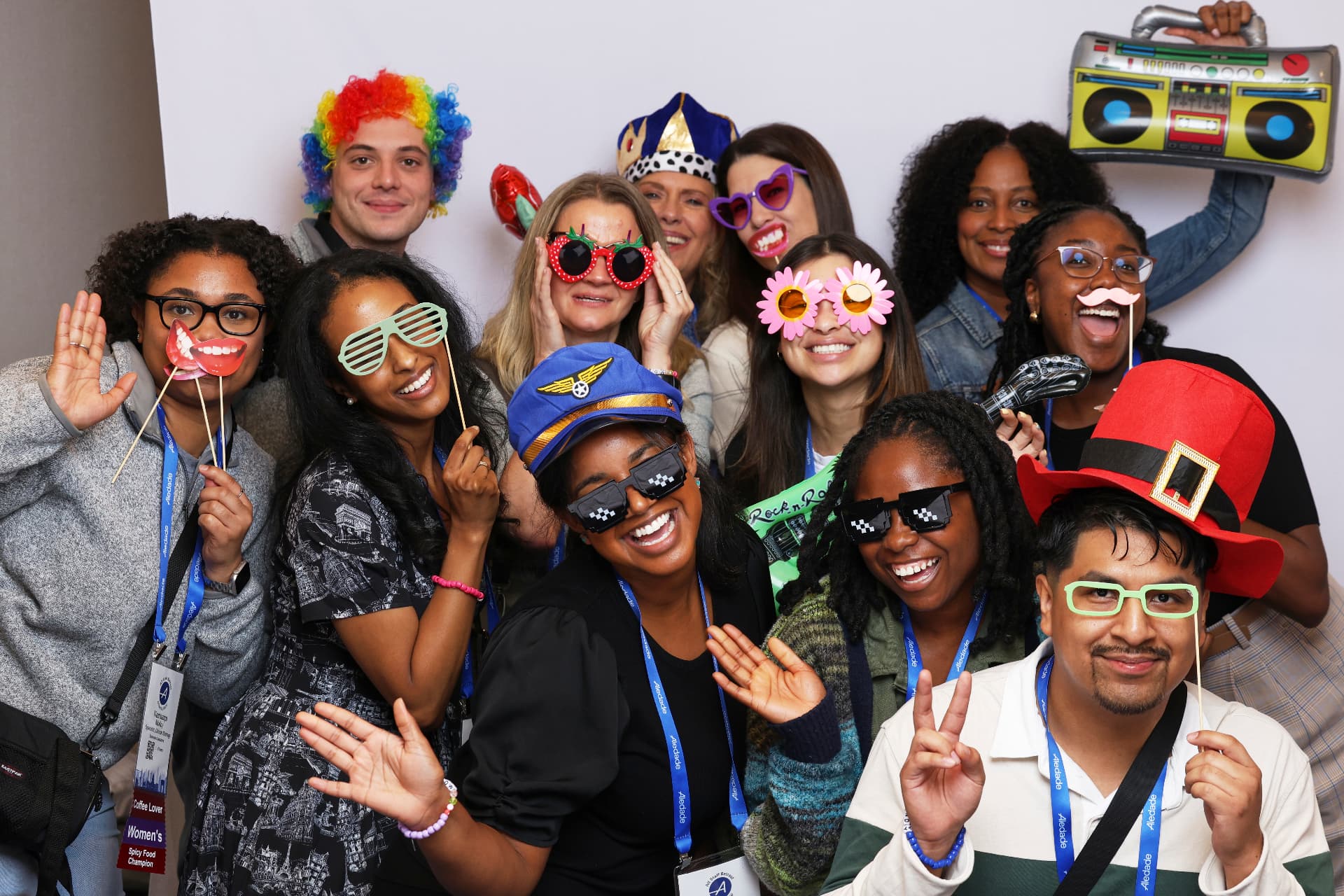 Group of Aledade attendees laughing with a rainbow wig, top hat and inflatable boombox at an Atlanta event photobooth