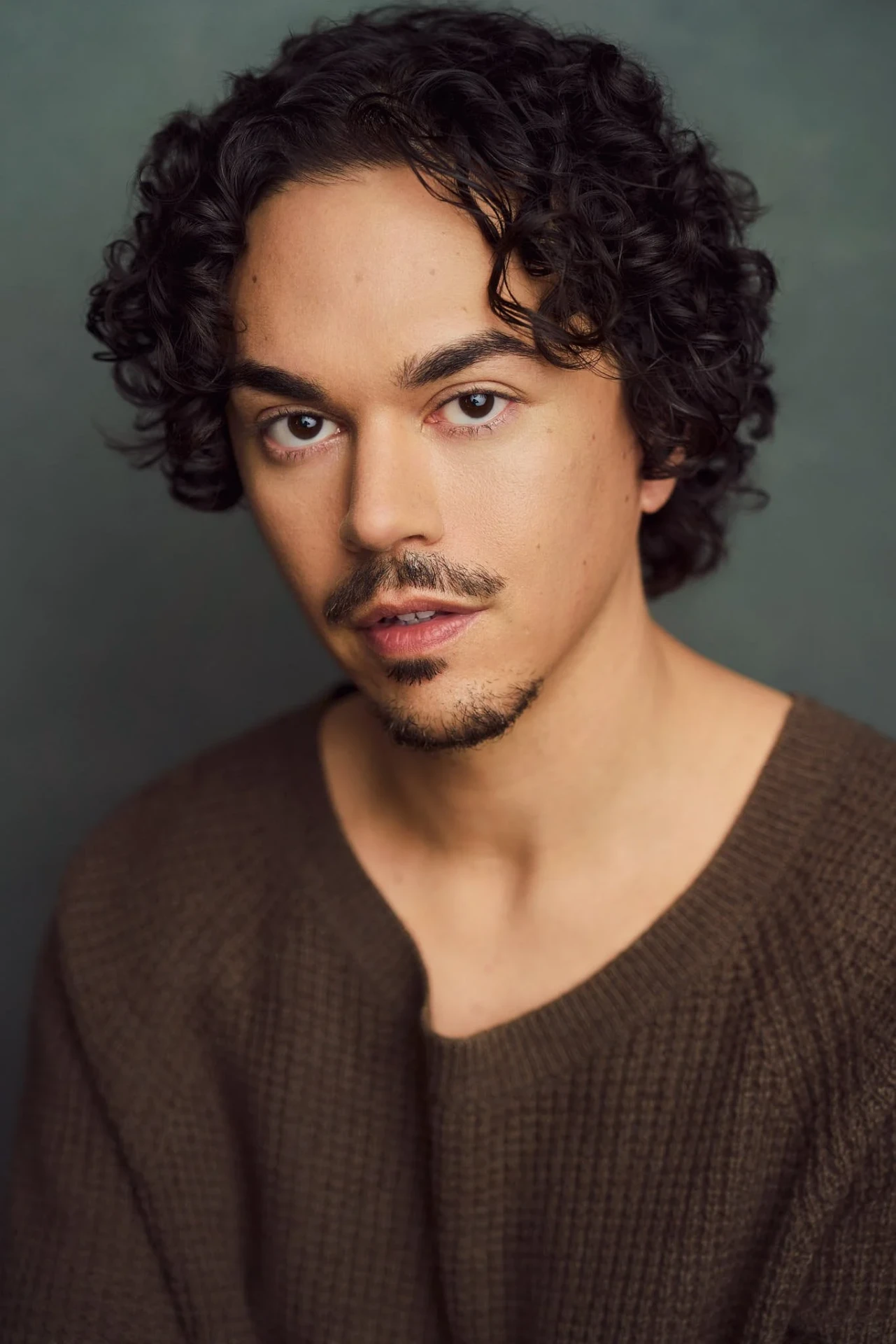 Editorial actor headshot of actor in a brown sweater on a dark green backdrop, photographed by an Atlanta actor headshot photographer