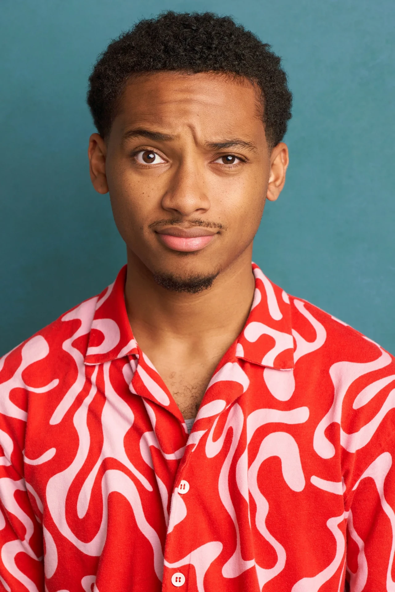 Comedic actor headshot in a red patterned shirt on a teal backdrop in Atlanta