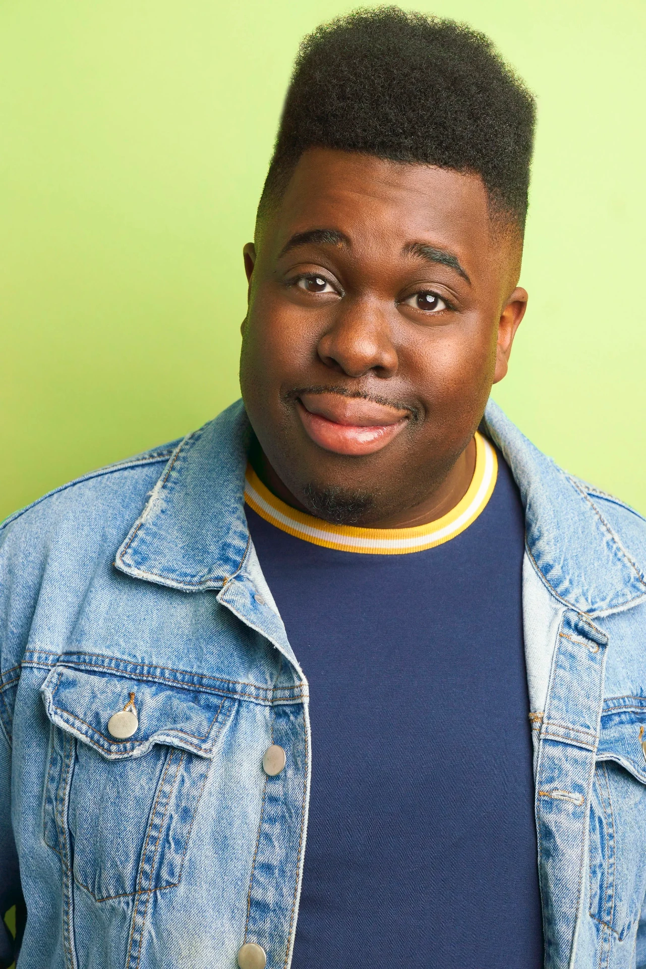 Editorial actor headshot of smiling actor in a denim jacket on a lime backdrop, photographed by an Atlanta actor headshot photographer