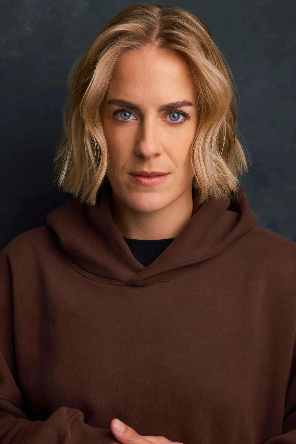 Actor headshot of a woman in a brown hoodie against a dark backdrop in Atlanta