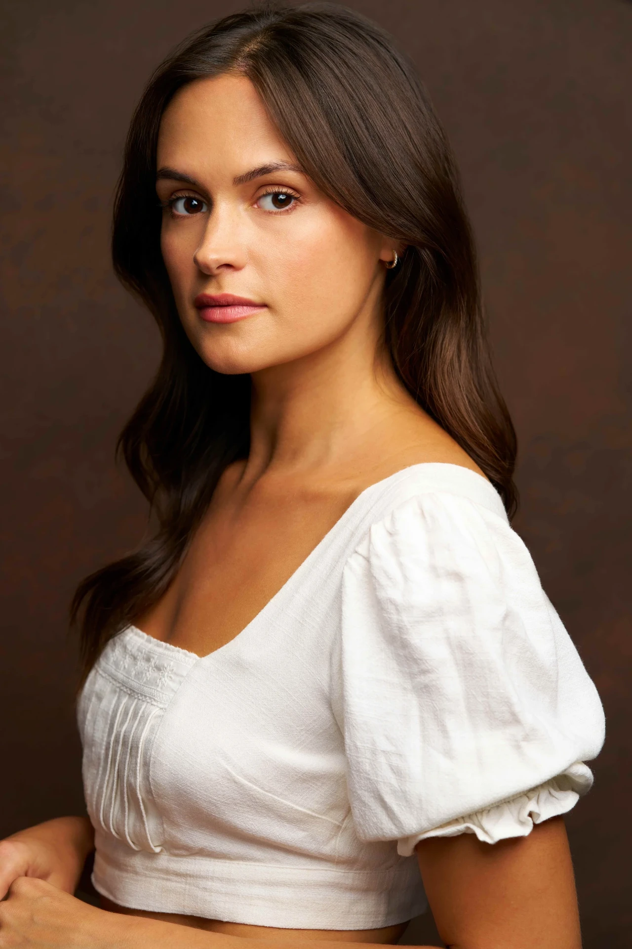 Editorial actor headshot of actress in a white puff-sleeve top on a brown backdrop, photographed by an Atlanta actor headshot photographer