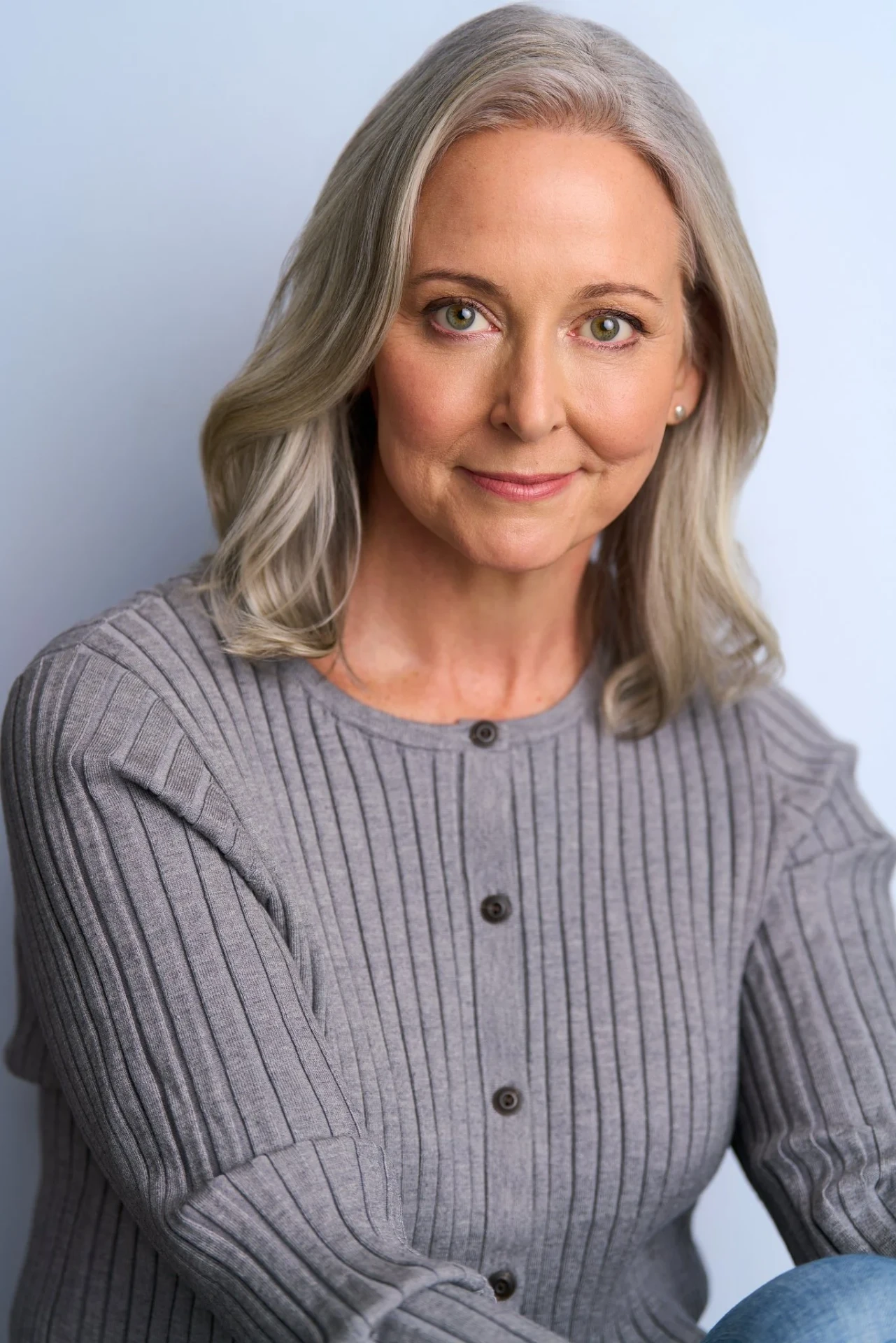 Editorial actor headshot of mature actress in a gray cardigan on a soft blue backdrop, photographed by an Atlanta actor headshot photographer