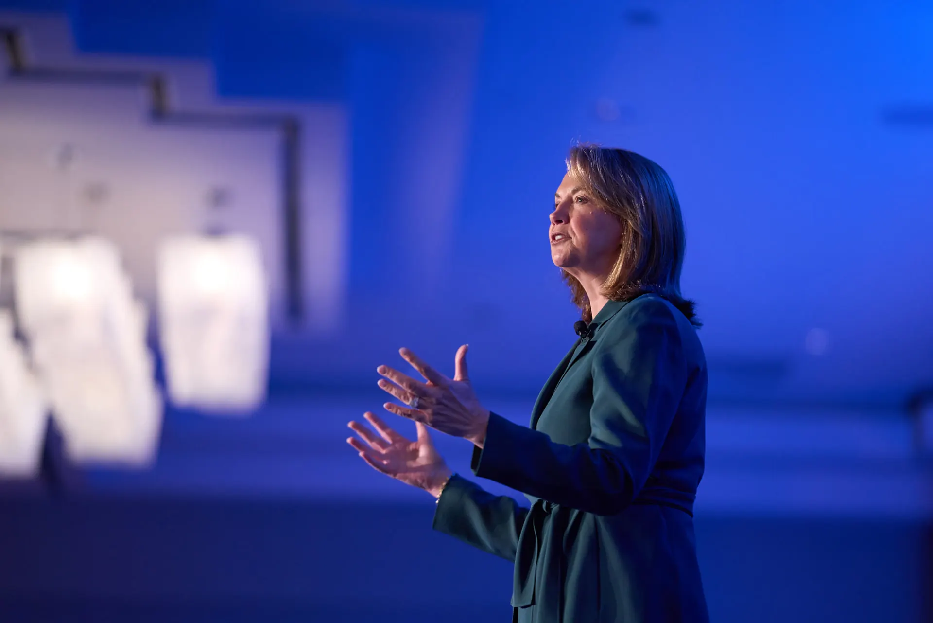 Speaker gesturing on a blue-lit conference stage