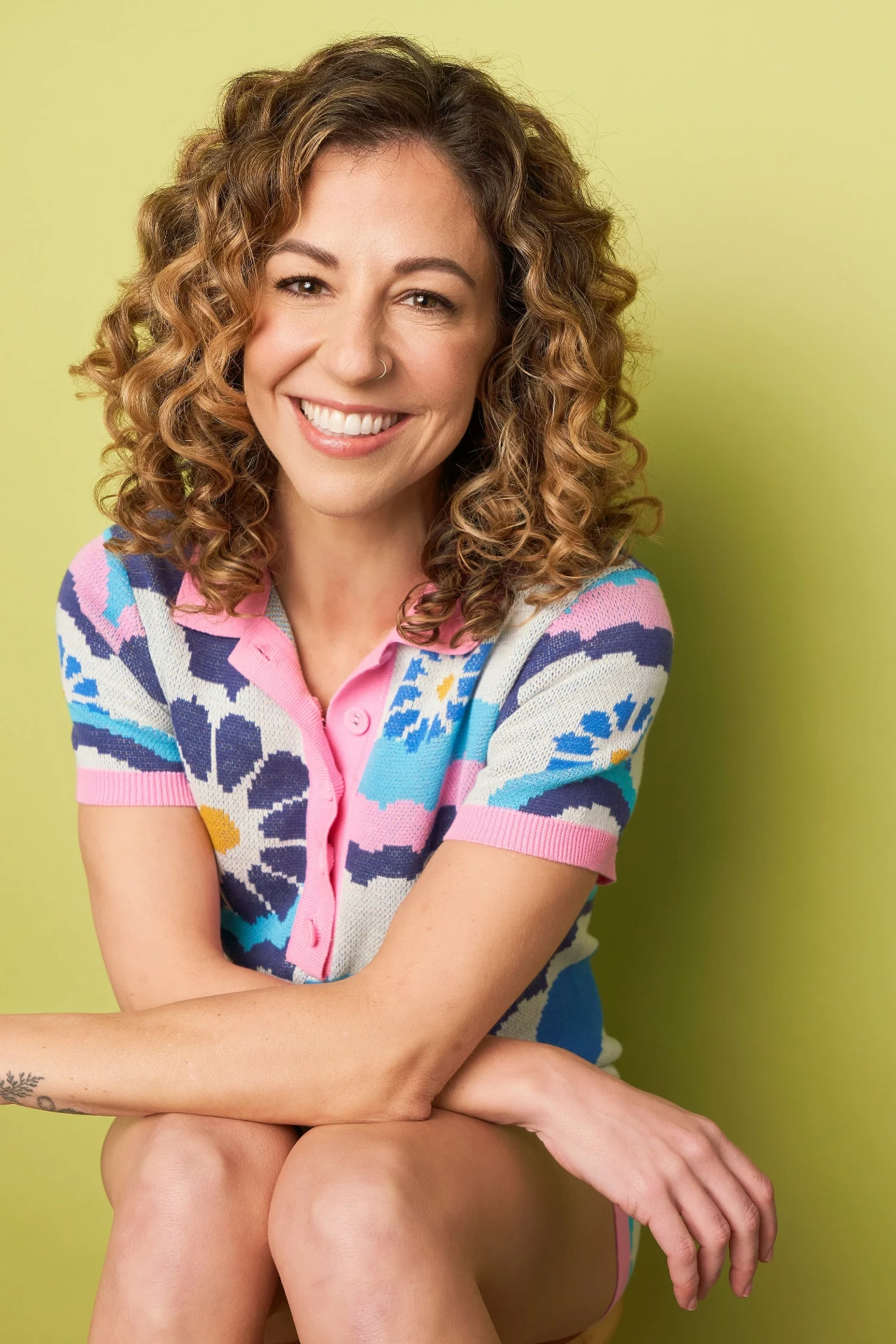 Editorial actor headshot of smiling curly-haired actress in a floral shirt on a lime backdrop, photographed by an Atlanta actor headshot photographer