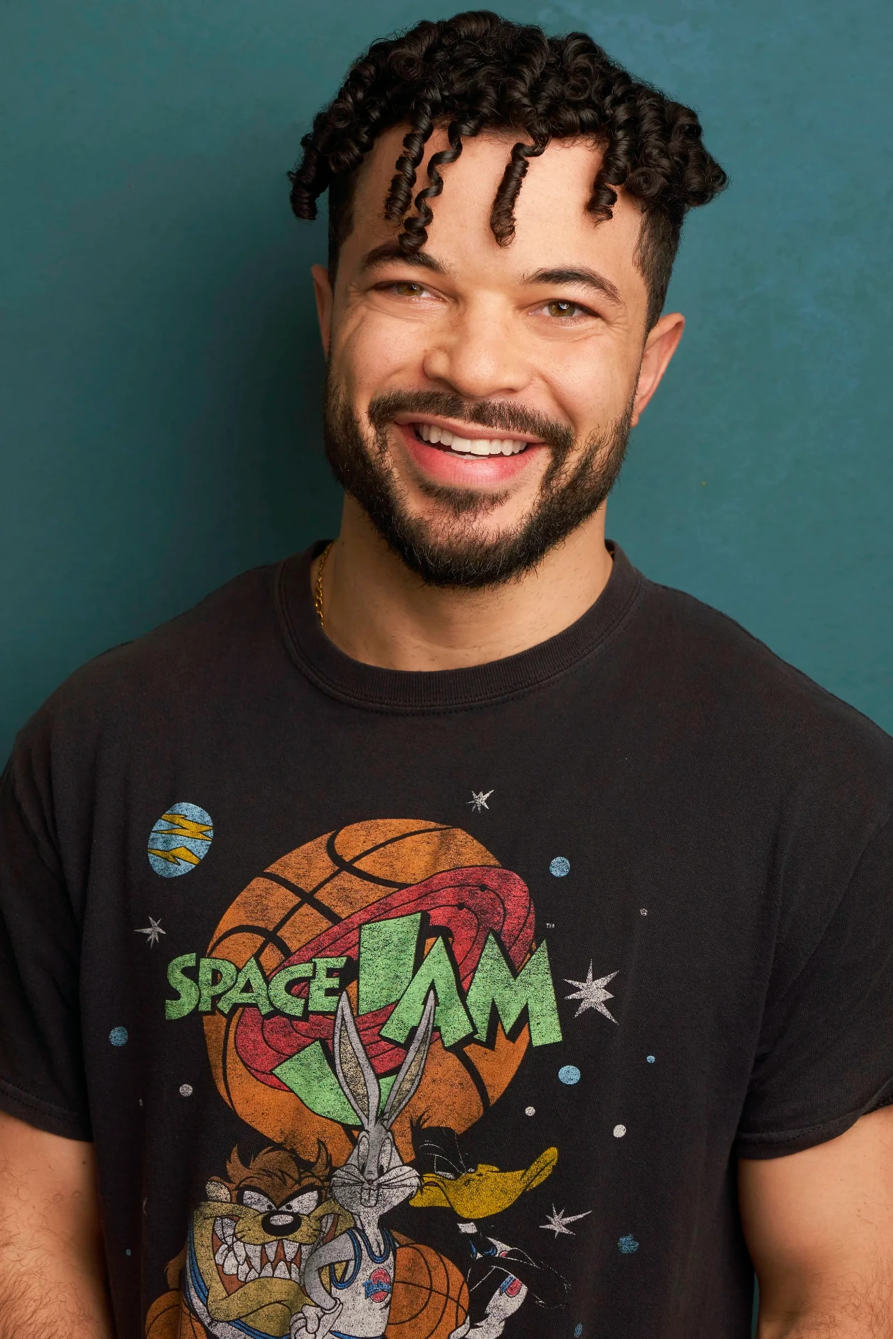 Editorial actor headshot of smiling actor in a graphic tee on a teal backdrop, photographed by an Atlanta actor headshot photographer