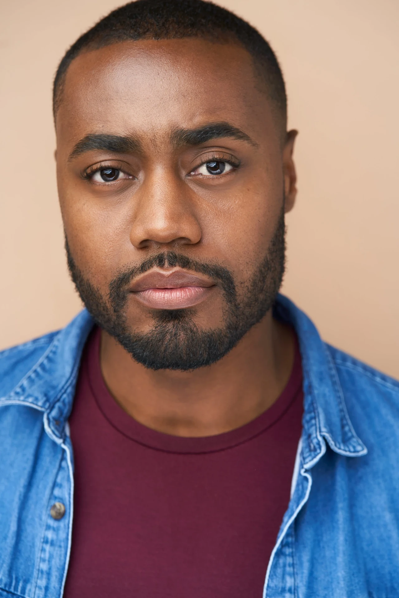 Editorial actor headshot of bearded actor in a denim shirt on a peach backdrop, photographed by an Atlanta actor headshot photographer