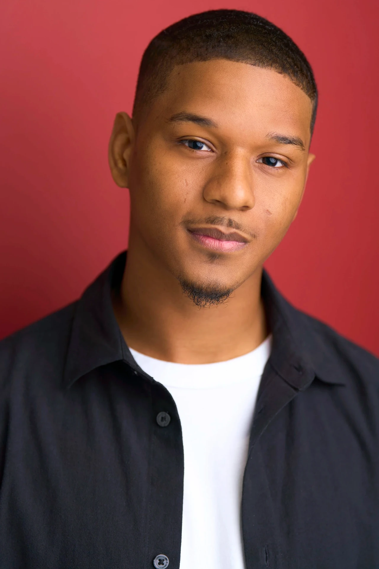 Editorial actor headshot of actor in a black overshirt on a red backdrop, photographed by an Atlanta actor headshot photographer