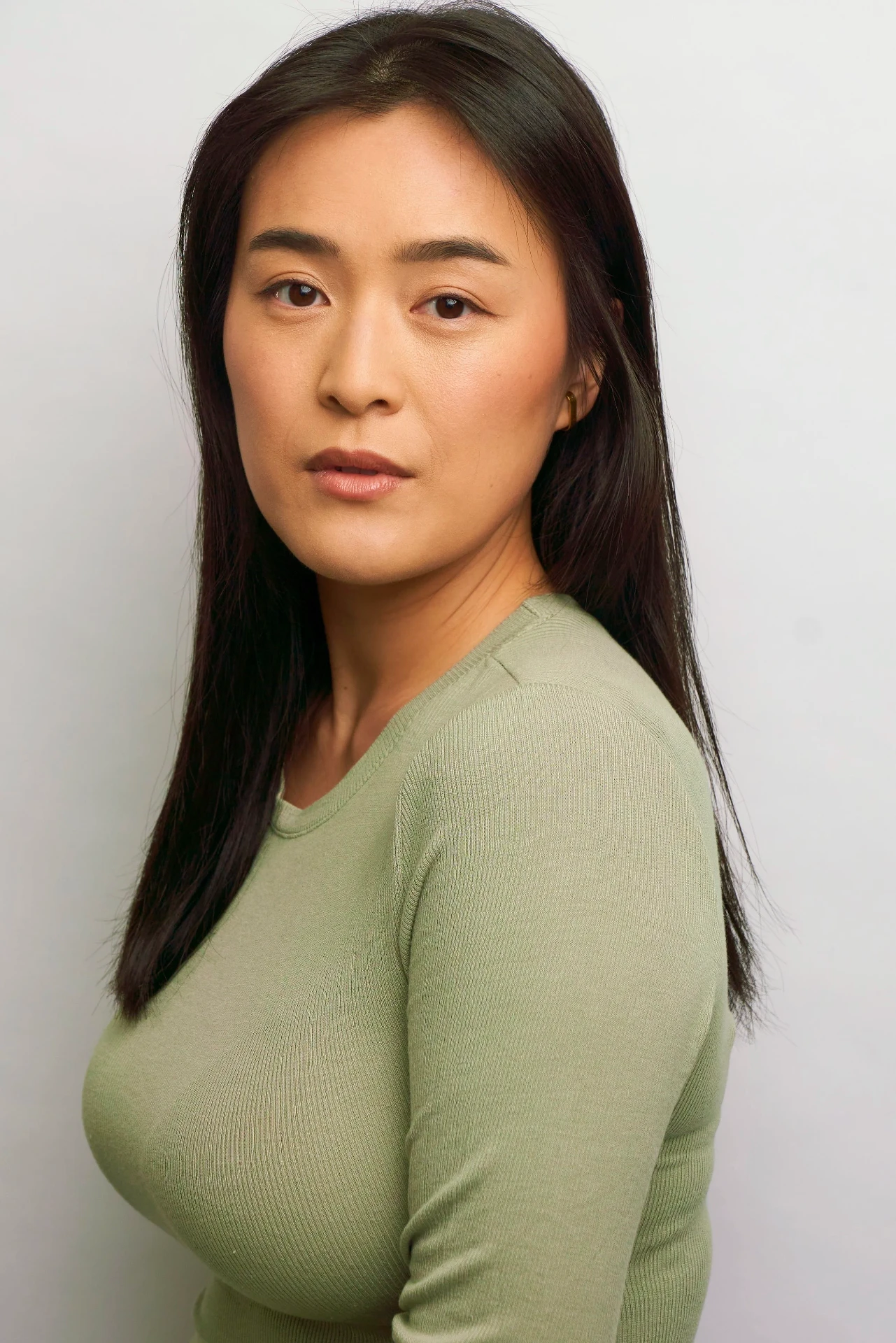 Editorial actor headshot of actress in a sage sweater on a white backdrop, photographed by an Atlanta actor headshot photographer