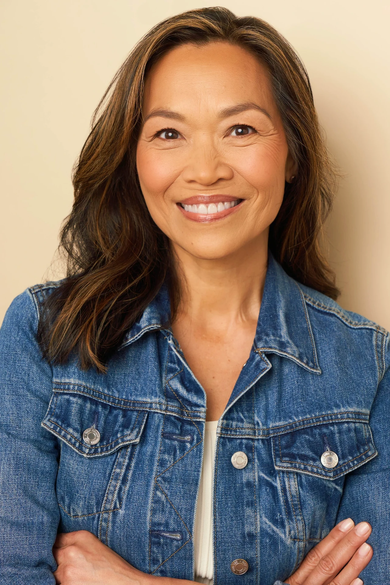 Editorial actor headshot of smiling actress in a denim jacket on a cream backdrop, photographed by an Atlanta actor headshot photographer