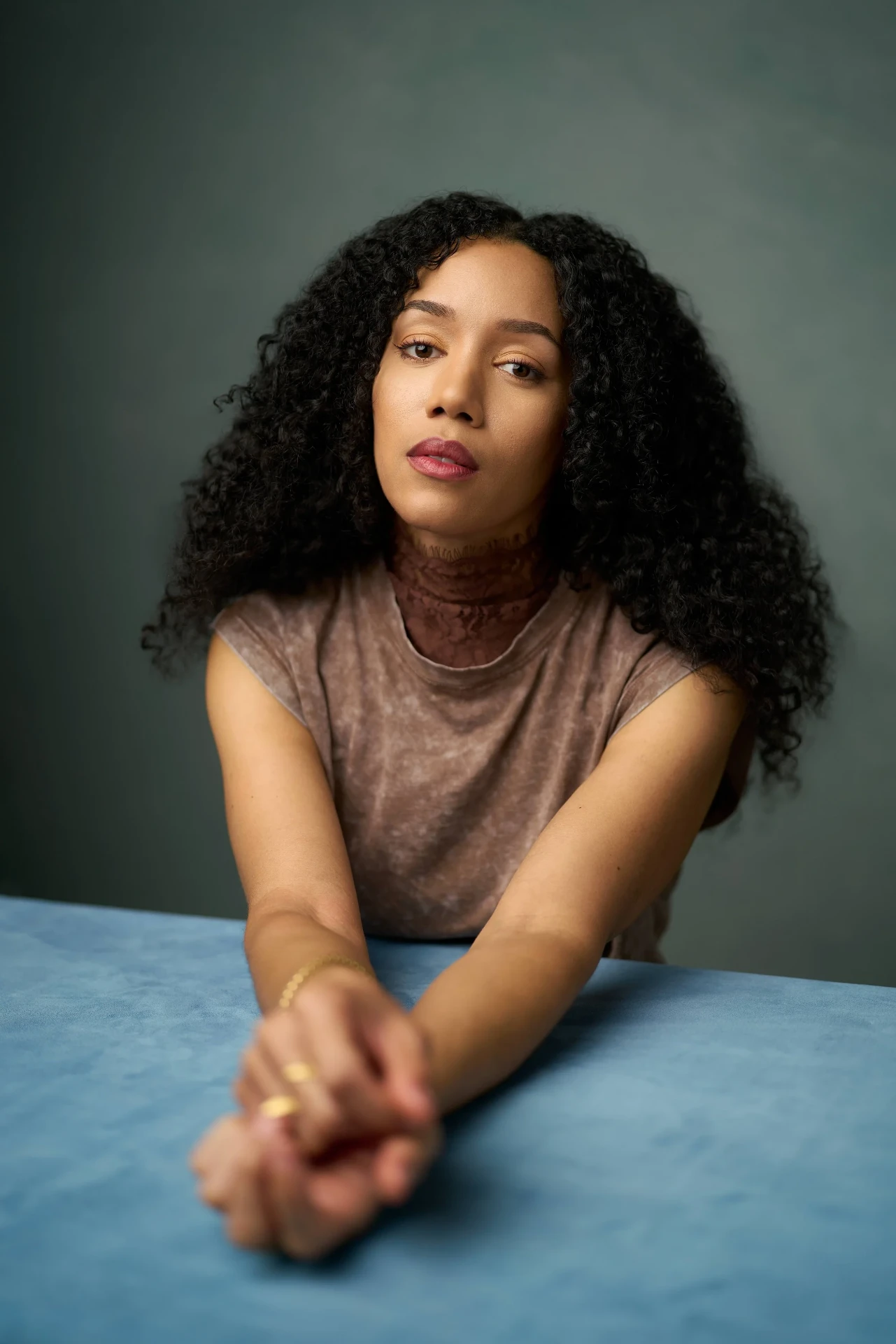 Editorial actress headshot with curly hair at a blue table in Atlanta