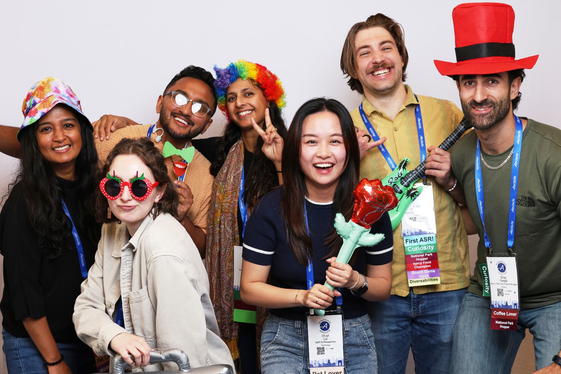 Seven Aledade conference guests posing with an inflatable guitar, rose and top hat at an Atlanta event photobooth