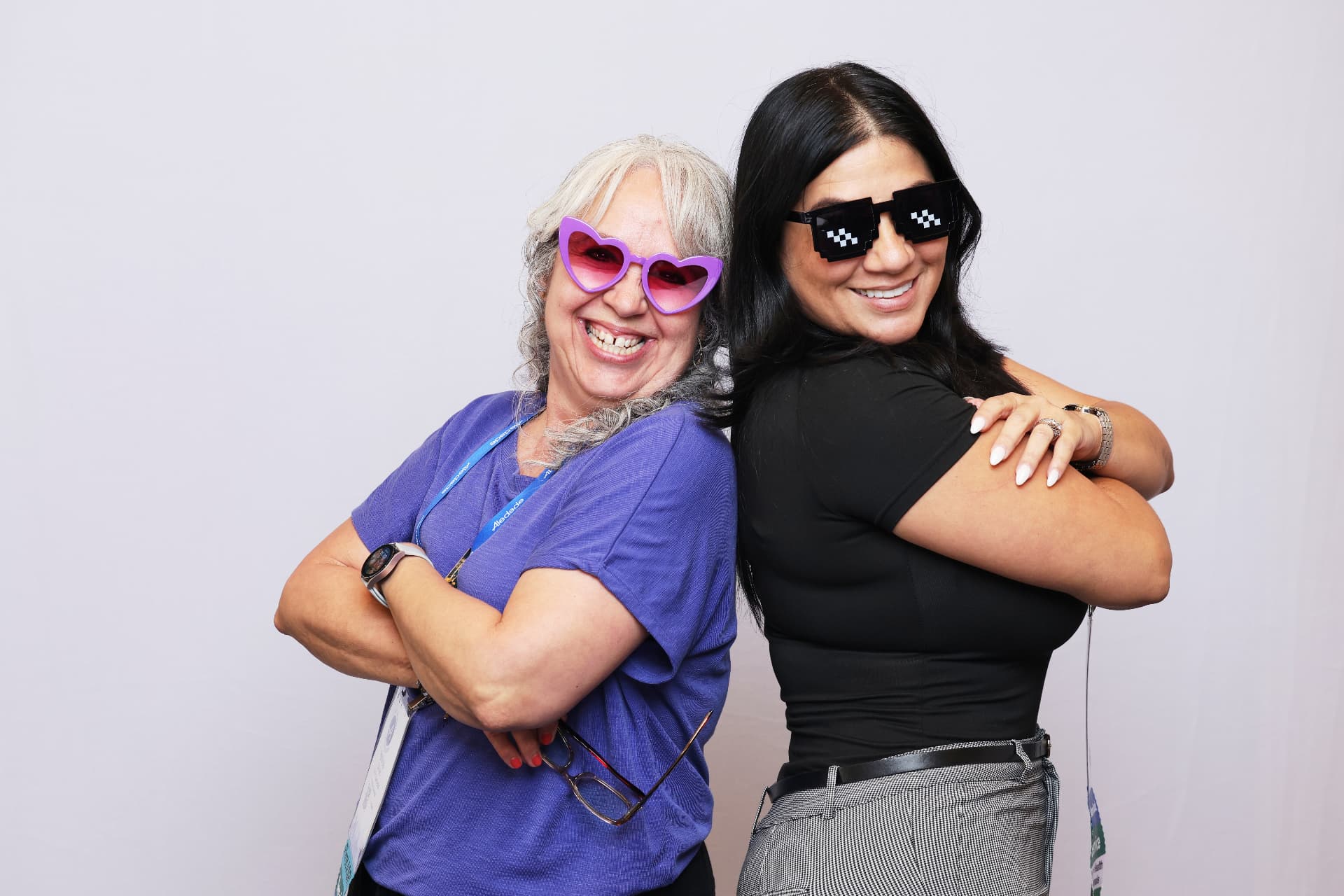 Two Aledade attendees posing back to back in novelty sunglasses at an Atlanta event photobooth