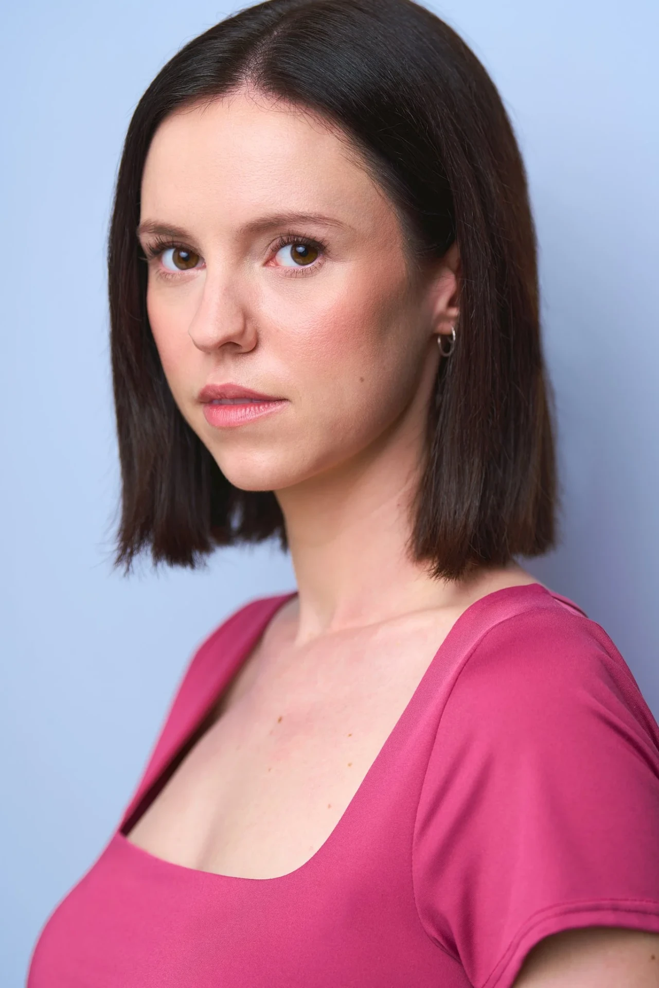 Actress headshot in a pink shirt on a soft blue backdrop in Atlanta