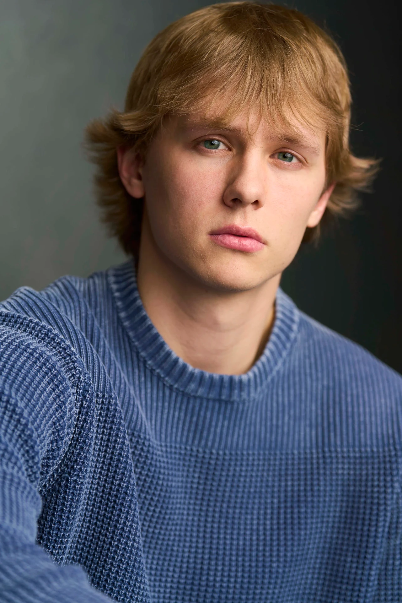 Editorial actor headshot of young actor in a blue sweater on a dark backdrop, photographed by an Atlanta actor headshot photographer