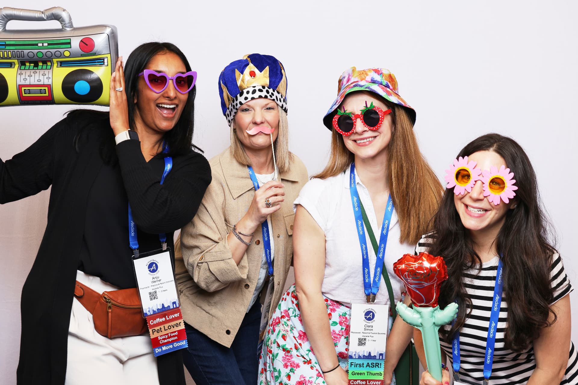 Four Aledade attendees posing with a crown, boombox prop and inflatable rose at an Atlanta event photobooth