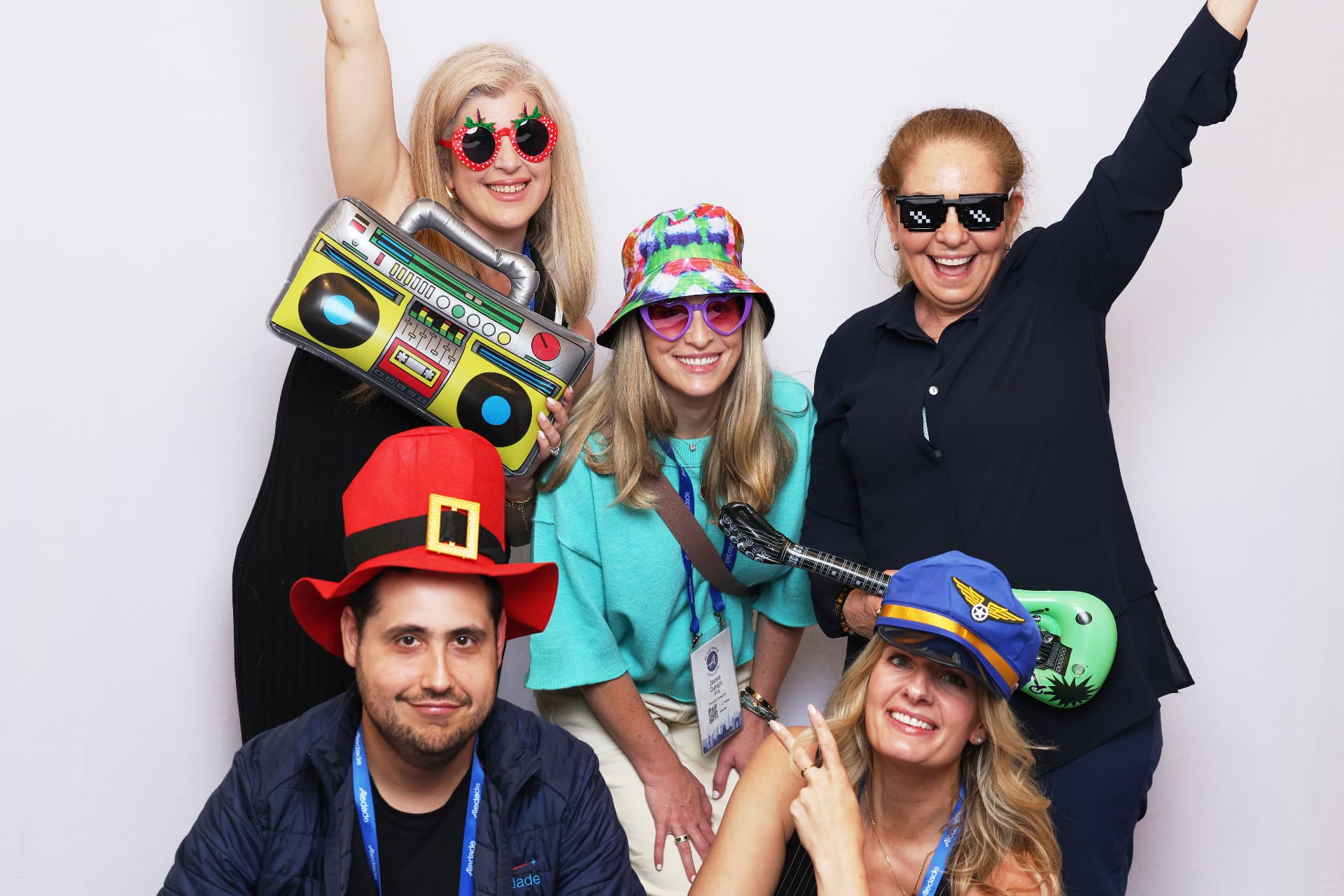 Five Aledade attendees cheering with novelty hats and sunglasses at an Atlanta event photobooth