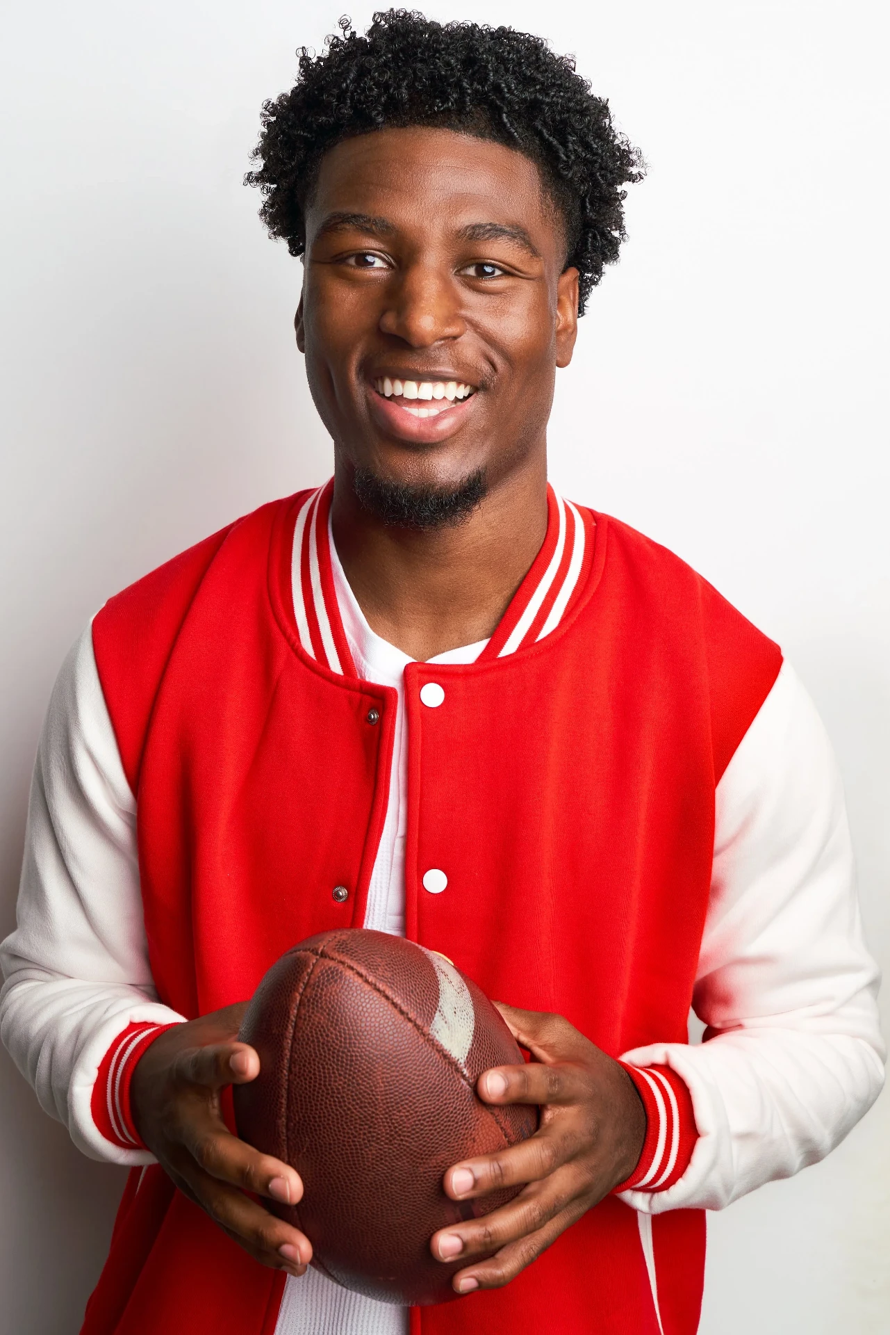 Commercial actor headshot in a red letterman jacket holding a football in Atlanta