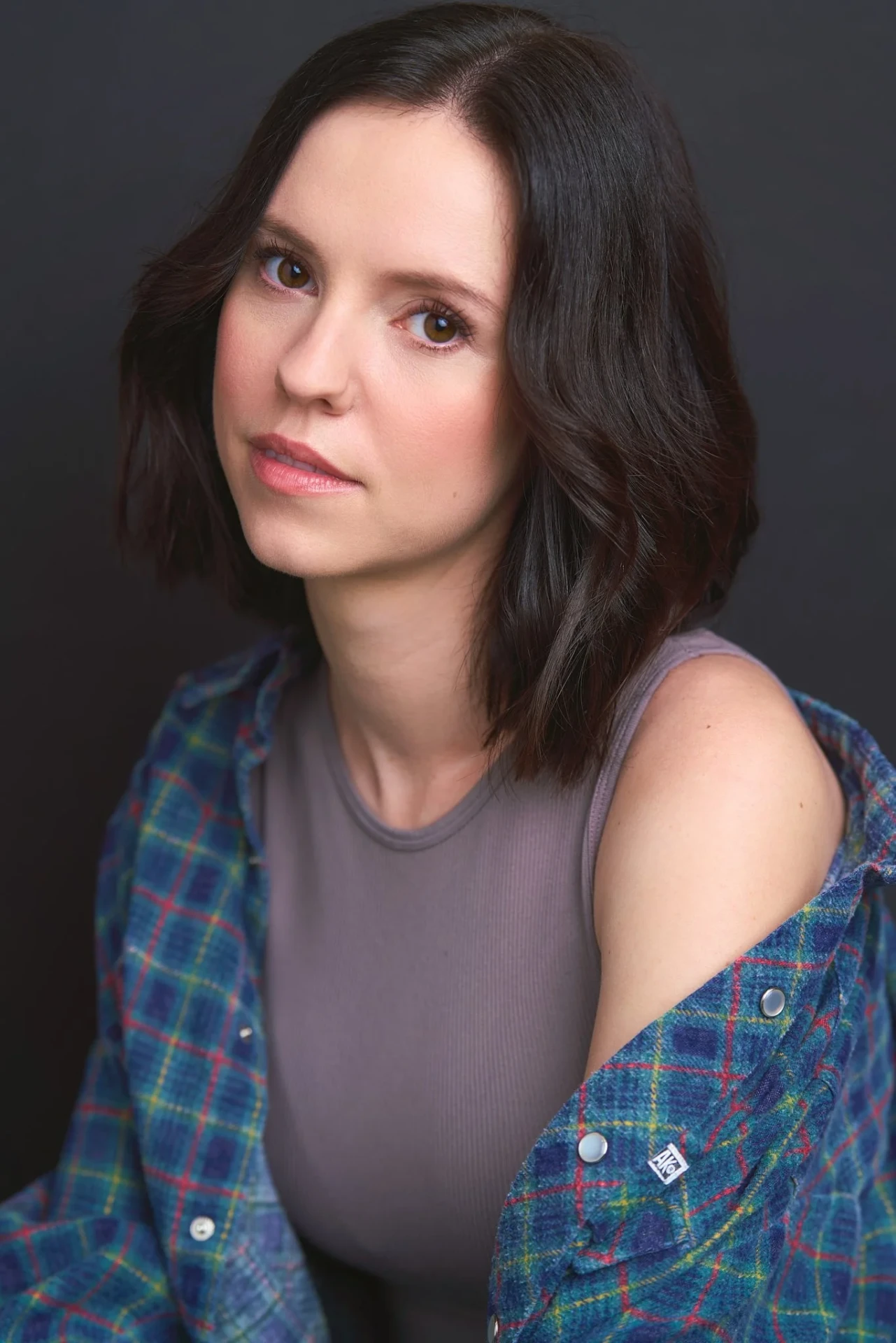 Theatrical actress headshot in a plaid shirt on a dark backdrop in Atlanta