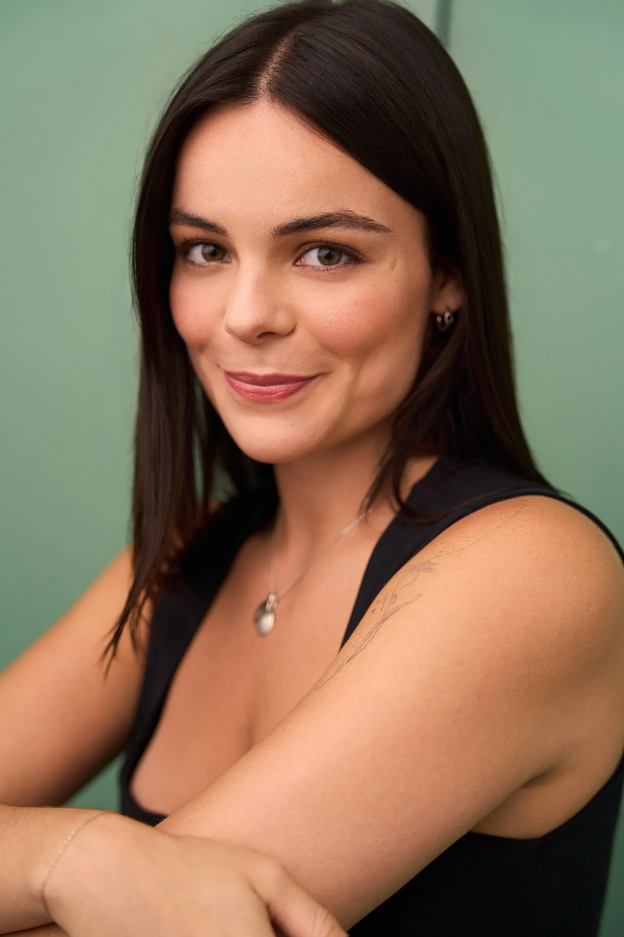Actress headshot in a black top on a sage green backdrop in Atlanta