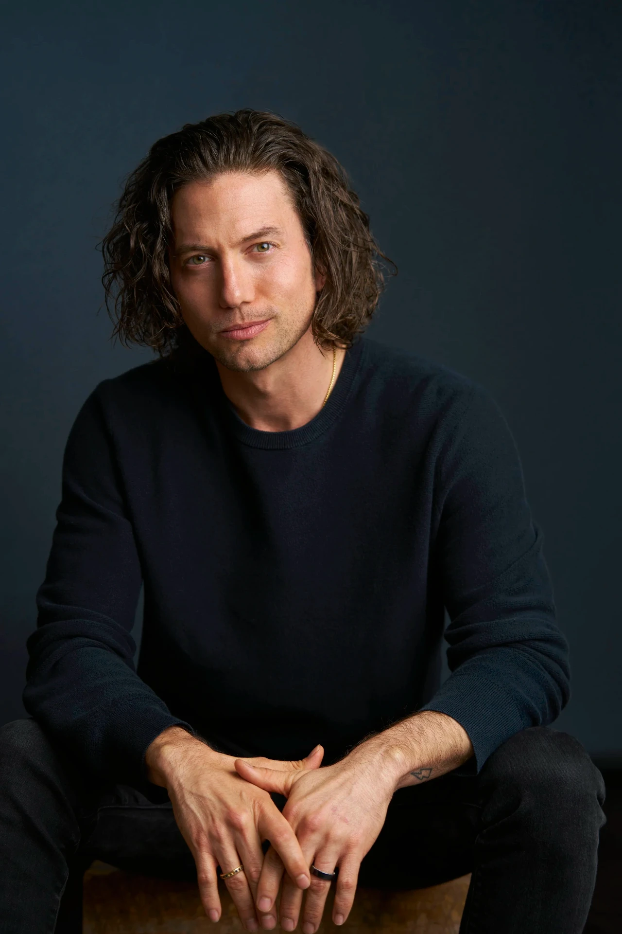 Editorial actor headshot of long-haired actor seated on a dark backdrop, photographed by an Atlanta actor headshot photographer