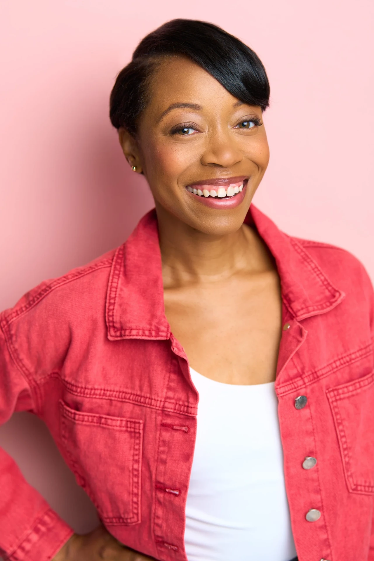 Smiling actress headshot in a red denim jacket on a pink backdrop in Atlanta