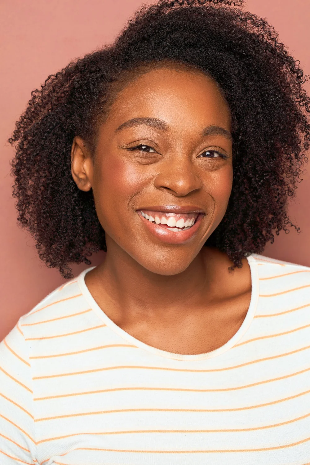 Smiling commercial actress headshot on a pink backdrop photographed in Atlanta